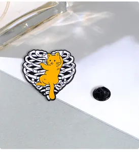 Macro detail of enamel cat brooch clinging to heart-shaped rib cage with back buckle