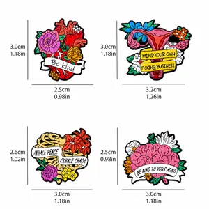 Vierteiliges Set Emaille-Pins mit anatomischen Organen und Blumen auf weißem Hintergrund