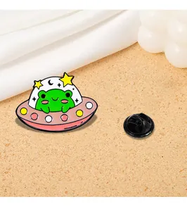 Detail of green frog in a pink UFO enamel pin with stars and black butterfly clasp