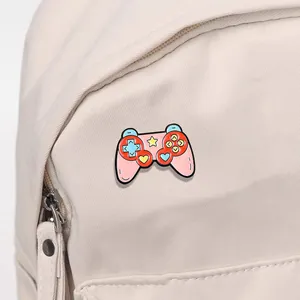Spilla smaltata a forma di controller rosa applicata su uno zaino di tela bianco