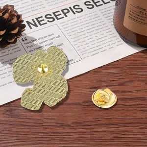 Golden flower enamel pin with needle back and butterfly clasp on dark wooden background