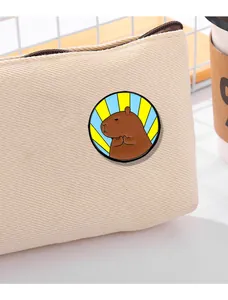 Χαριτωμένη καρφίτσα σμάλτου Capybara σε στάση προσευχής σε μπεζ υφασμάτινη τσάντα