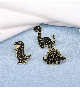 Detailed view of three black enamel dinosaur pins with golden constellation patterns
