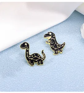 Detailed close-up of set of two black dinosaur enamel pins with gold starry sky patterns