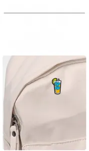 Detail of cute sun and cold drink enamel pins decorated on a white canvas bag surface