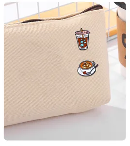 Detail of coffee enamel pins set on a beige canvas bag showing creative latte and cold brew art