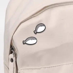 Set of two cute Sacabambaspis cartoon enamel pins pinned on a canvas backpack