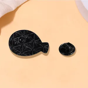 Detail of black Sacabambaspis enamel pin showing geometric star texture and butterfly clasp