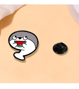 Macro view of cartoon fish enamel pin eating watermelon with rubber back clasp