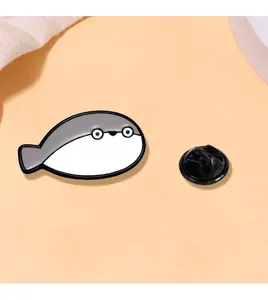 Detail of cute fish enamel pin on orange background with black rubber clasp