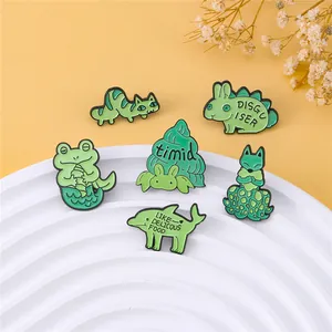 Detailed close-up of six creative green animal enamel pins on a white tiered display stand