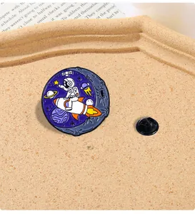 Détail d'un pin's émaillé astronaute sur fusée avec un fond de ciel étoilé cosmique