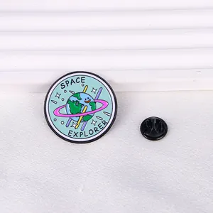 Detail of a Space Explorer enamel pin with a smiling earth and star ring on white fabric