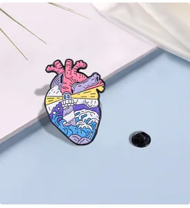 Detail of anatomical heart enamel pin featuring lighthouse and ocean wave motifs
