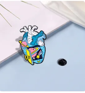 Macro detail of surreal anatomical heart enamel pin featuring starry night and portal design