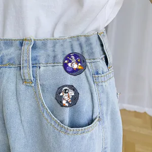 Pins en émail astronaute et fusée dessin animé attachés sur un tissu en denim
