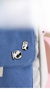 Détail de pins émaillés chat noir et blanc mignons fixés sur un sac en toile bleu clair