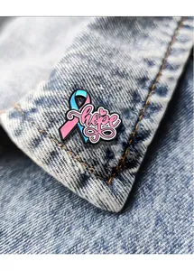 Detail einer rosa-blauen Emaille-Schleifenbrosche mit Hope-Schriftzug auf Denim