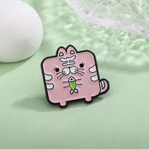 Cute pink cartoon cat enamel pin holding a fish on a fresh green background