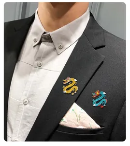 Detailansicht goldener und blauer Drachen-Emaille-Anstecknadeln am Revers eines Blazers