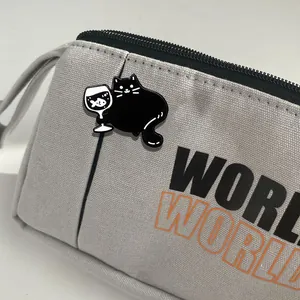 Insigne en émail chat noir rigolo avec verre à vin sur une pochette en toile grise