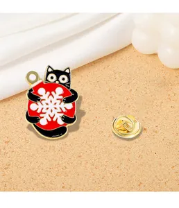 Macro detail of a cute black cat enamel pin holding a red snowflake Christmas ornament