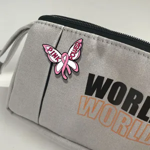 Pink ribbon butterfly enamel pin badge on gray canvas bag for breast cancer awareness