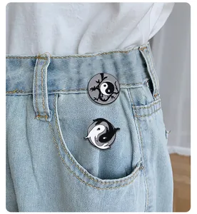 Detail of Tai Chi yin yang enamel pins on denim pocket with dragon and koi fish motifs