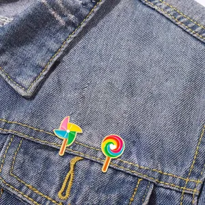 Lollipop and windmill enamel pins set on a blue denim jacket pocket for cute decoration