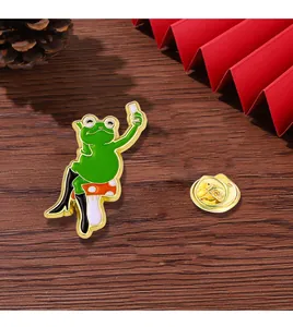 Detail of funny frog on mushroom enamel pin with gold butterfly clutch on wood background