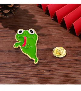 Macro detail of cartoon green frog enamel pin with gold clutch back on wooden surface