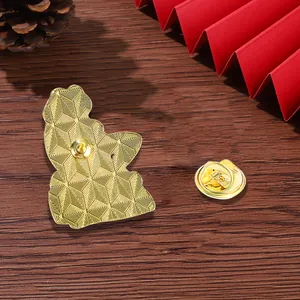 Golden frog cartoon brooch back view with metal clutch on dark wood background