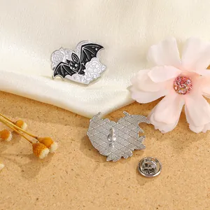 Broche chauve-souris gothique en émail avec rose blanche sur soie et fond de bois