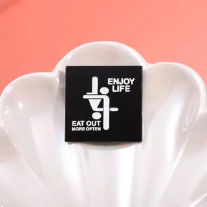 Macro shot of square black metal pin featuring minimalist graphics and Enjoy Life text