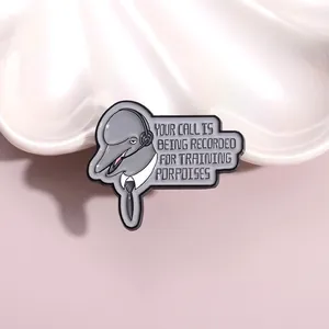 Close-up of enamel dolphin pin with headset and training porpoises text detail