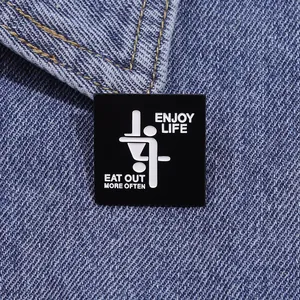 Square black enamel pin with Enjoy Life text on a blue denim collar background
