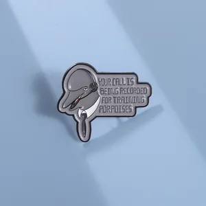 Detail of dolphin enamel pin with 'Training Porpoises' text on light blue background