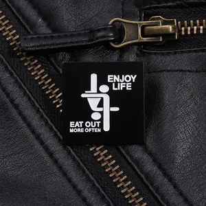 Close-up of Enjoy Life metal badge with text on black textured leather jacket