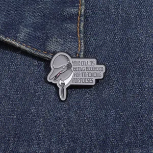 Detail of dolphin enamel pin with Your Call Is Being Recorded text on denim background