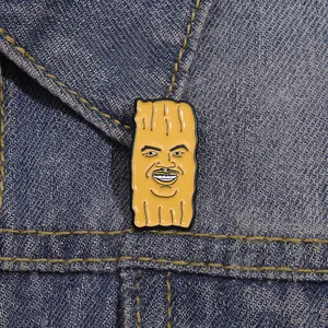 Détail d'un pin's en émail jaune avec visage de dessin animé sur veste en jean