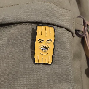 Gros plan d'un badge émaillé jaune rigolo avec portrait de dessin animé sur un sac