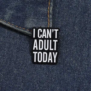 Enamel brooch with 'I CAN'T ADULT TODAY' slogan on dark blue denim fabric texture