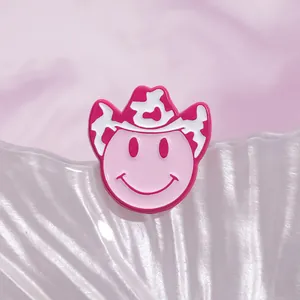 Macro shot of pink enamel smiley face pin with cow print cowboy hat on shell base