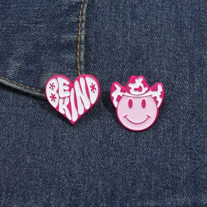 Pink heart BE KIND and cowboy hat smiley face enamel pins set on denim fabric