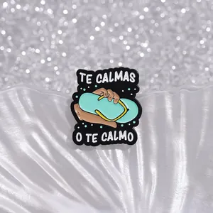 Detail einer Emaille-Brosche mit Flip-Flop-Motiv und lustigem Te Calmas O Te Calmo Text