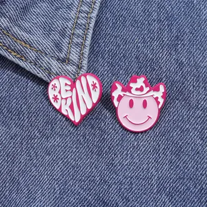 Detail of pink cowgirl hat and heart enamel pins pinned on a blue denim jacket fabric