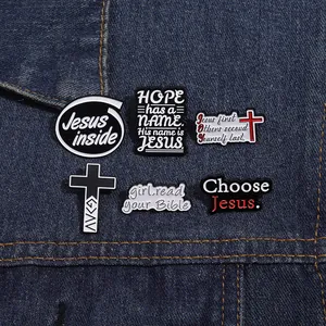 Detailed view of six black and white religious enamel pins on blue denim fabric background