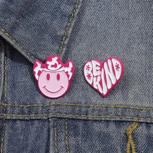 Detail of pink cowgirl hat and heart enamel pins with Be Kind text on denim jacket