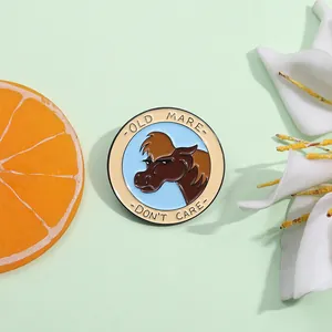 Detail of round enamel lapel pin featuring a brown mare and Don't Care slogan text