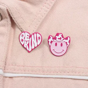 Close-up of pink cowgirl hat and heart enamel pins on denim fabric texture